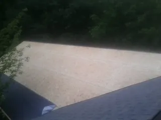New OSB roof sheathing installed beside an existing shingle roof in Defiance