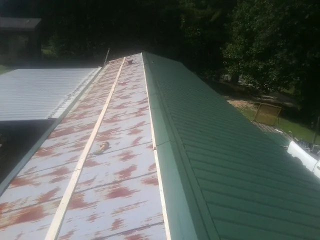 Old rusted panels beside newly installed green metal roofing — Wind Damage Roof Repair by Roofing Brothers in Defiance